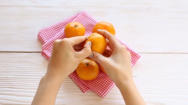 Mujer joven pelar mandarina — Vídeos de Stock