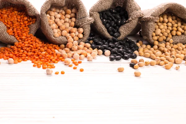 Tigelas de várias leguminosas em fundo de madeira, comida saudável, comida vegan . — Fotografia de Stock