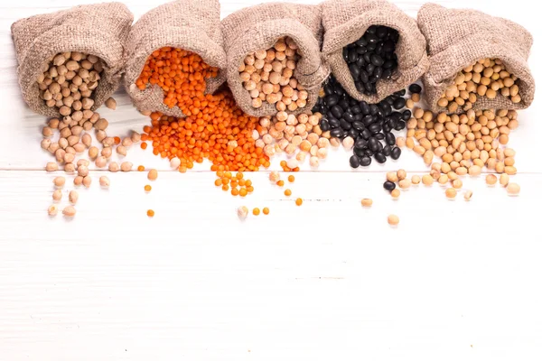 Cuencos de varias legumbres sobre fondo de madera, comida saludable, comida vegana . — Foto de Stock