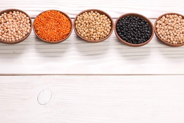 Kommen van verschillende peulvruchten op houten achtergrond, gezonde voeding, vegan food. — Stockfoto