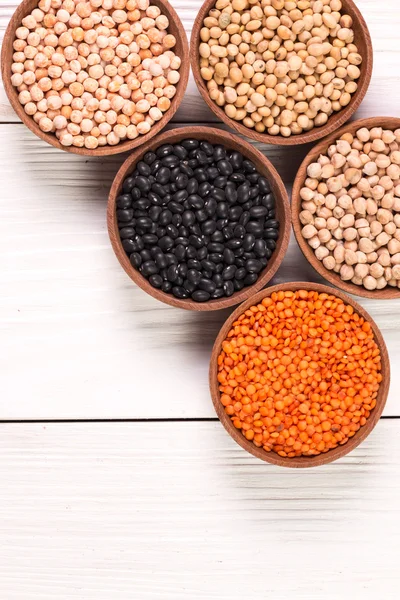 Cuencos de varias legumbres sobre fondo de madera, comida saludable, comida vegana . — Foto de Stock