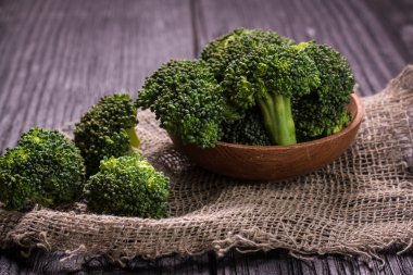 Kahverengi tabakta bir sürü taze yeşil brokoli, ahşap arka planda.