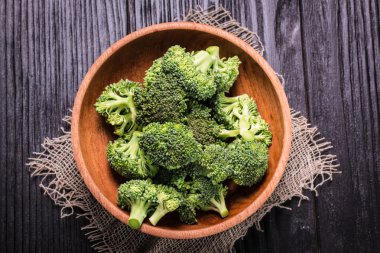 Kahverengi tabakta bir sürü taze yeşil brokoli, ahşap arka planda.