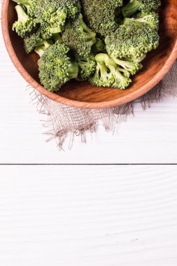 Kahverengi tabakta bir sürü taze yeşil brokoli, ahşap arka planda.