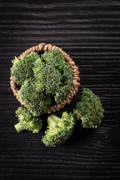 Mazzo di broccoli verdi freschi su piatto marrone su fondo di legno — Foto Stock