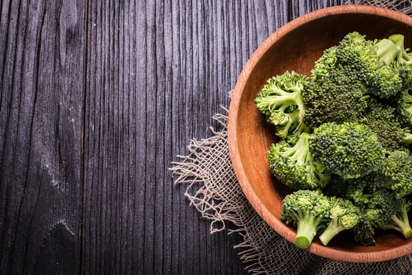 Bunch of fresh green broccoli on brown plate over wooden background — Stock Photo, Image