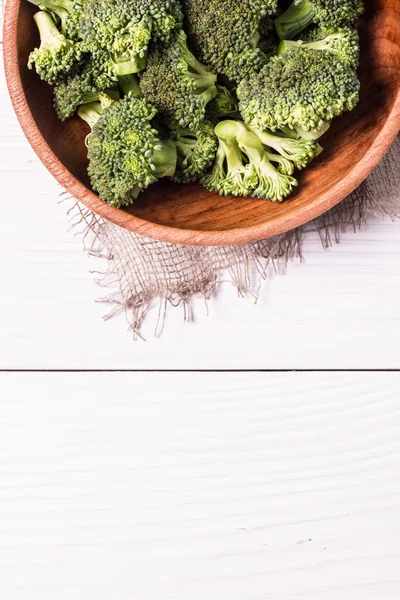 Bunch of fresh green broccoli on brown plate over wooden background — Stock Photo, Image