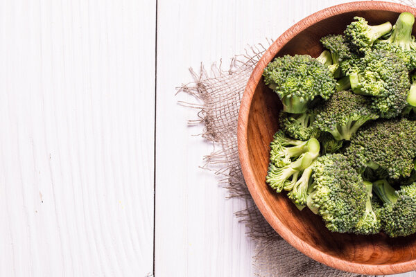 Bunch of fresh green broccoli on brown plate over wooden background