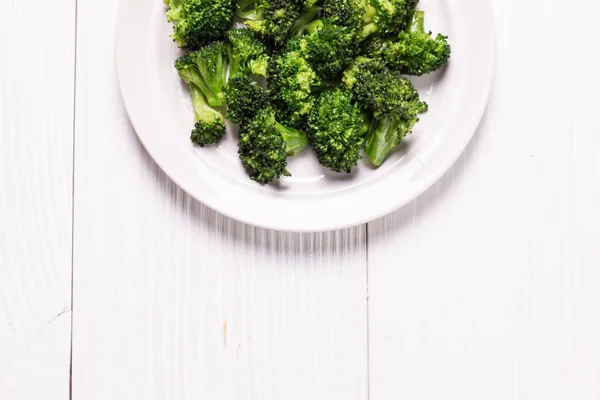 Bunch of fresh green broccoli on brown plate over wooden background — Stock Photo, Image