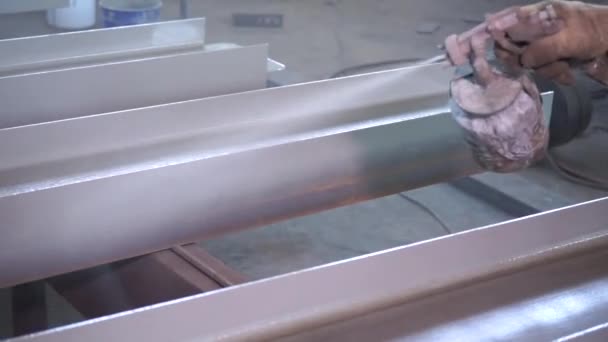 Poedercoating van metalen onderdelen. Werknemer in beschermingspak spuit poederverf uit pistool op metalen producten — Stockvideo