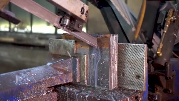 Řezací stroj, Pásová pila pro průmyslové řezání kovové tyče a použití chladicí kapaliny ve světle modré scéně.Průmyslový nástroj. — Stock video