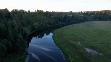 4K hava yaz erken sabah kaliteli video görüntüleri el değmemiş yemyeşil çam ağacı ormanı gölün etrafını sardı, sakin sular bulutları yansıtıyor, bir baraj, ada, Rusya 'nın küçük bir kasabasındaki kumsal.