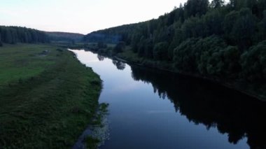 4K hava yaz erken sabah kaliteli video görüntüleri el değmemiş yemyeşil çam ağacı ormanı gölün etrafını sardı, sakin sular bulutları yansıtıyor, bir baraj, ada, Rusya 'nın küçük bir kasabasındaki kumsal.