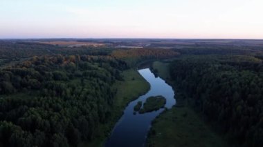 4K hava yaz erken sabah kaliteli video görüntüleri el değmemiş yemyeşil çam ağacı ormanı gölün etrafını sardı, sakin sular bulutları yansıtıyor, bir baraj, ada, Rusya 'nın küçük bir kasabasındaki kumsal.