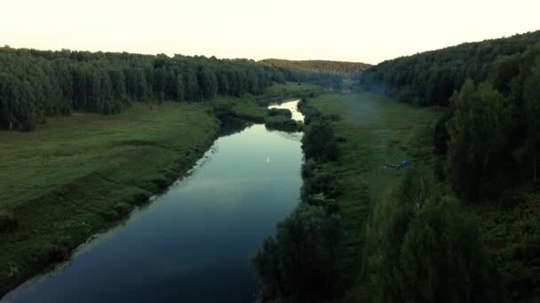 Vista aérea: Voo sobre o belo rio e a madeira verde. Pôr do sol luz suave com céu nublado pastel. Paisagem mágica. Resolução 4K . — Vídeo de Stock