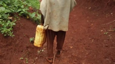 Genç bir Afrikalı Çocuk Uganda bir kuyuda bir sarı su kabı ile yürüme