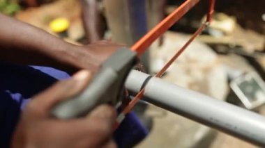 Yeni bir de kırsal Uganda, Afrika yüklemek için kullanılan bir plastik tüp testere Afrikalı bir adam