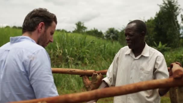 Caucasian man chatting to African man by a water well in Uganda, Africa — Stock Video