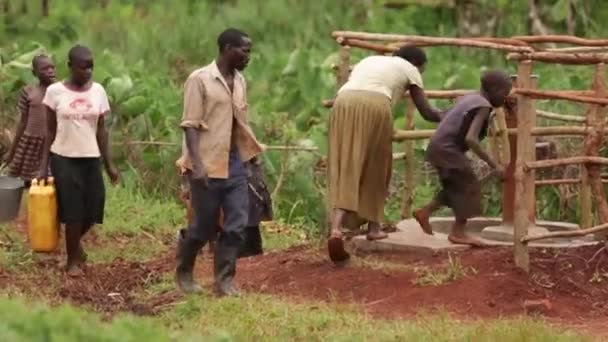 An African family filling up yellow water containers at a well — Stock Video