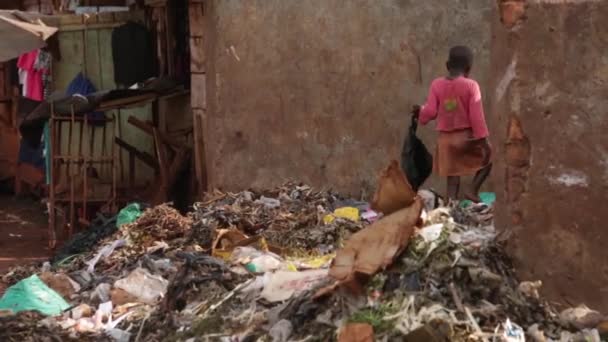 Niño africano mirando a través de un pozo de basura en un tugurio, Masindi, Uganda, septiembre de 2013 — Vídeo de stock