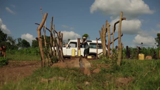 Una mujer africana llena un recipiente de agua con una bomba de agua en una parte rural de Masindi, Uganda, septiembre de 2013 — Vídeos de Stock