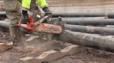 Kıvılcım büyük bir boruyla kesmek için kesme makinesi kullanan adam