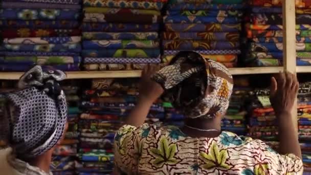Afryki dama w tradycyjne stroje w sklepie tkaniny patrząc na tkaniny, Moshi, Kenii, Marzec 2013 — Wideo stockowe