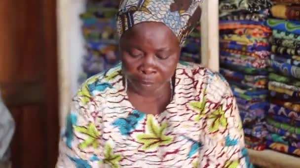 Africká žena v tradičním oblečení v obchodě textilie při pohledu na tkaniny, Tereza, Keňa, březen 2013 — Stock video