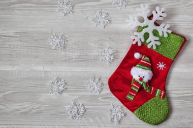 Beyaz kar taneleri ve ahşap arka planda kardan adam olan çorabın Noel süsleri.