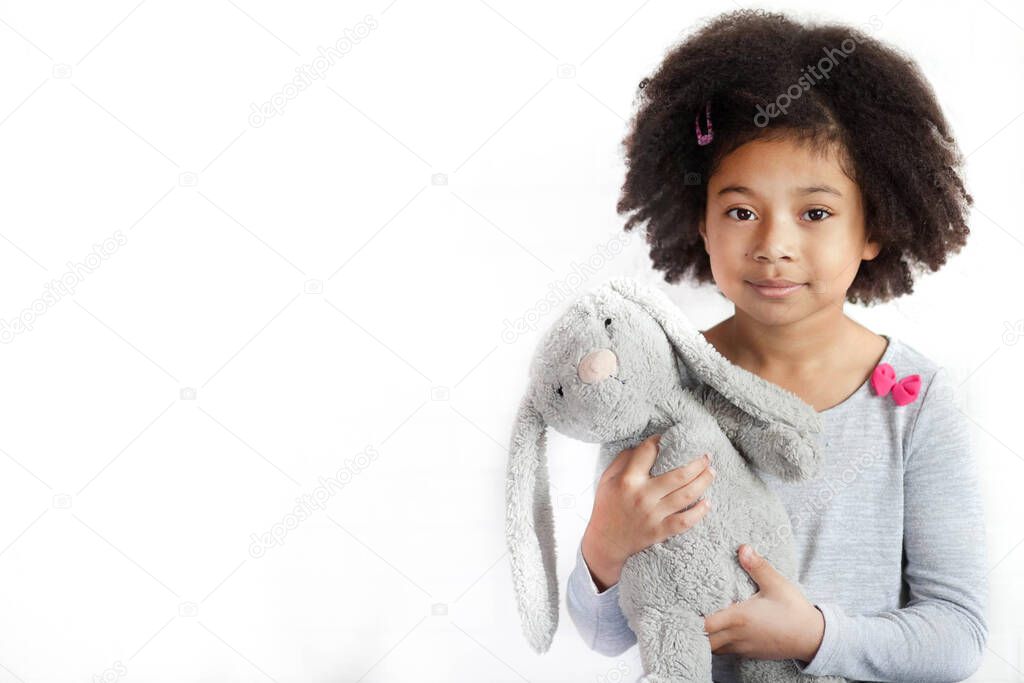 the adorable little girl holding the cute bunny toy in the studio