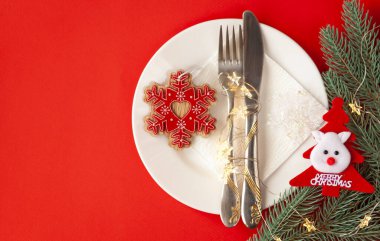 Kırmızı arka planda dekoratif sembollerle çizilmiş Noel masası servis ediliyor.