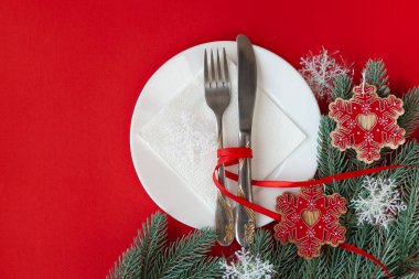 Kırmızı arka planda dekoratif sembollerle çizilmiş Noel masası servis ediliyor.