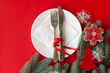 Kırmızı arka planda dekoratif sembollerle çizilmiş Noel masası servis ediliyor.