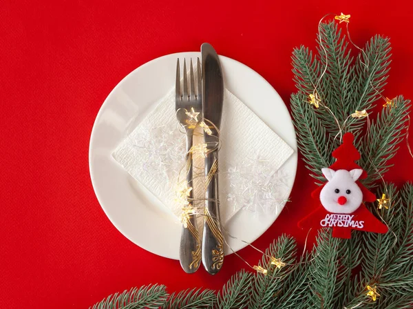 Kırmızı arka planda dekoratif sembollerle çizilmiş Noel masası servis ediliyor.