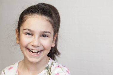 Uzun saçlı, gülümseyen küçük bir kızın portresi