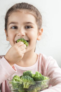 Brokoliyi cam kasede tutan genç kız.