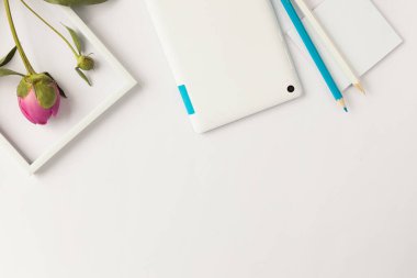 Üzerinde bir fincan kahve, bir çiçek ve beyaz bir kalem olan boş bir defterin üst görüntüsü.