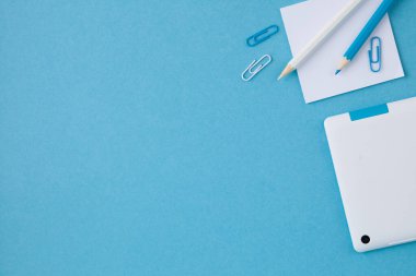 Mavi arka planda ofis malzemelerinin üst görüntüsü