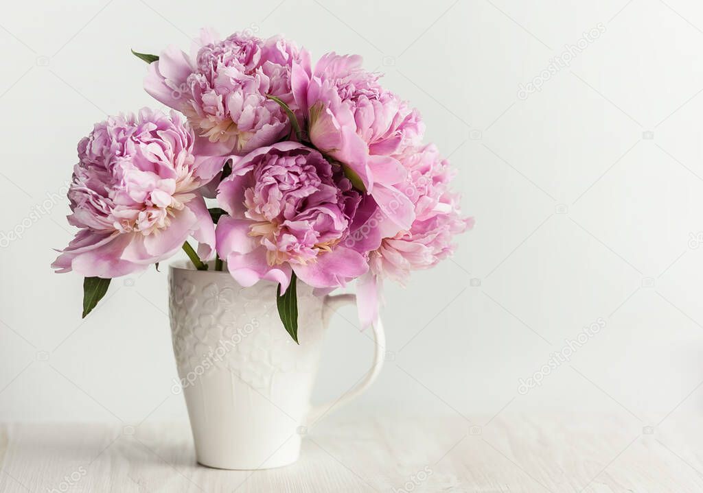 pink peonies in a vase on a white background