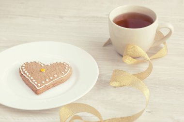 kalp şeklinde kurabiyeler çikolata ve ahşap masada kahve.