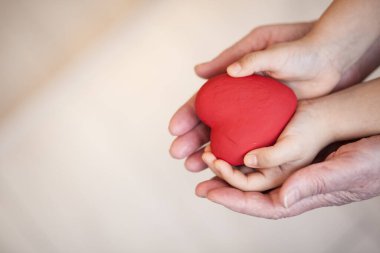 Kalp elinde kırmızı gül tutan kadının ellerinde.