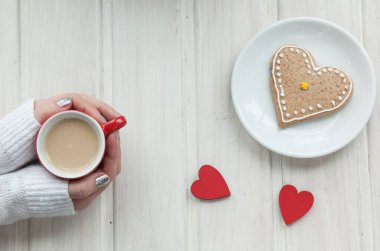 Ahşap arka planda bir fincan kahve ve kalp şeklinde.