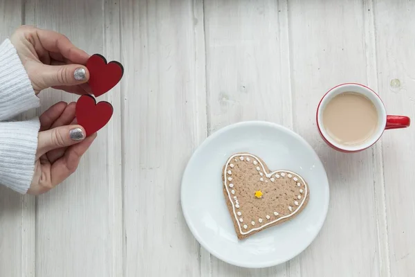 hands holding cup of coffee with heart shape on wooden table