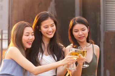 Asyalı genç kadınlar beyaz şarap kadehiyle tezahürat yapıp kadeh kaldırarak yaz partisinde kutlama yapıyorlar. Kutlama, ilişki ve arkadaşlık kavramı.