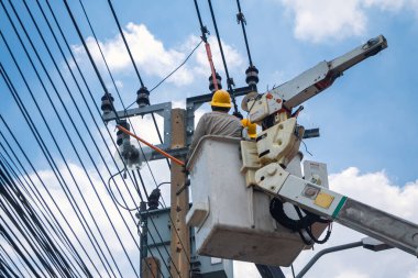 Vinçteki elektrikçiler çalışıyor ve şehirde elektrik hatları, trafo ve telefon kabloları kuruyor..