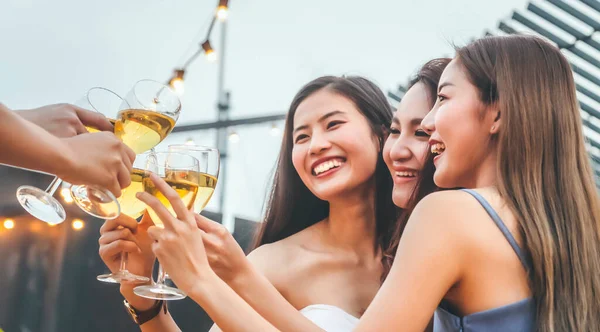 happy asian woman teenagers cheering and toast with white sparkling wine glass to celebrating at dinner party in summertime. selective focus. celebration, relationship and friendship concept.