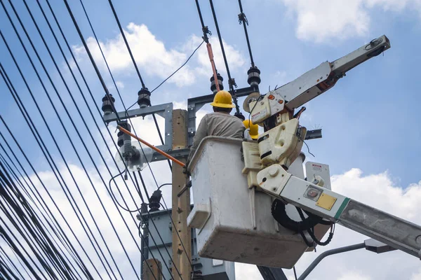 Vinçteki elektrikçiler çalışıyor ve şehirde elektrik hatları, trafo ve telefon kabloları kuruyor..