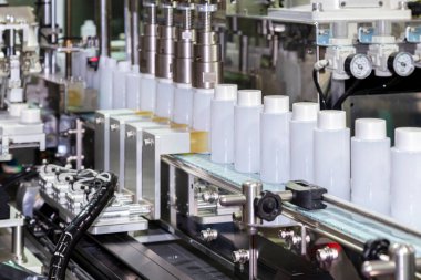 Kozmetik ve cilt bakımı ürünlerinde otomatik kaplama ve etiketleme makinesinin taşıyıcı bandı üzerinde hareket eden beyaz plastik şişe. Kozmetik endüstrisi ve ai teknoloji makineleri konsepti.