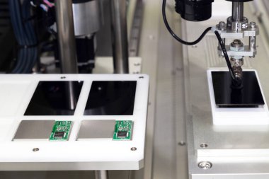 Üretim hattında çalışan ve yeni yenilikçi ve yüksek teknoloji akıllı telefon fabrikasında akıllı telefon ekranları monte eden vakumlu otomatik robot kolu..