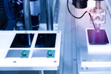 Üretim hattında çalışan ve yeni yenilikçi ve yüksek teknoloji akıllı telefon fabrikasında akıllı telefon ekranları monte eden vakumlu otomatik robot kolu..